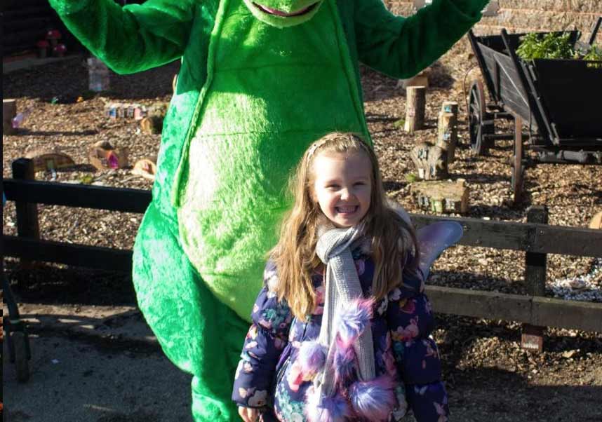 A little girl posing with a dragon at Marsh Farm